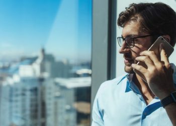 Venture capital investor speaking with entrepreneur based in London via the phone whilst hes in a high rise office