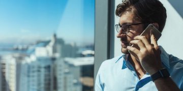 Venture capital investor speaking with entrepreneur based in London via the phone whilst hes in a high rise office