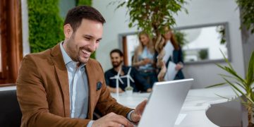 Entrepreneur sitting at his desk smiling because he is successful