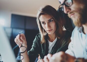 Two employees working at a laptop to implement best practise cyber security to ensure the business is safe connected to the internet