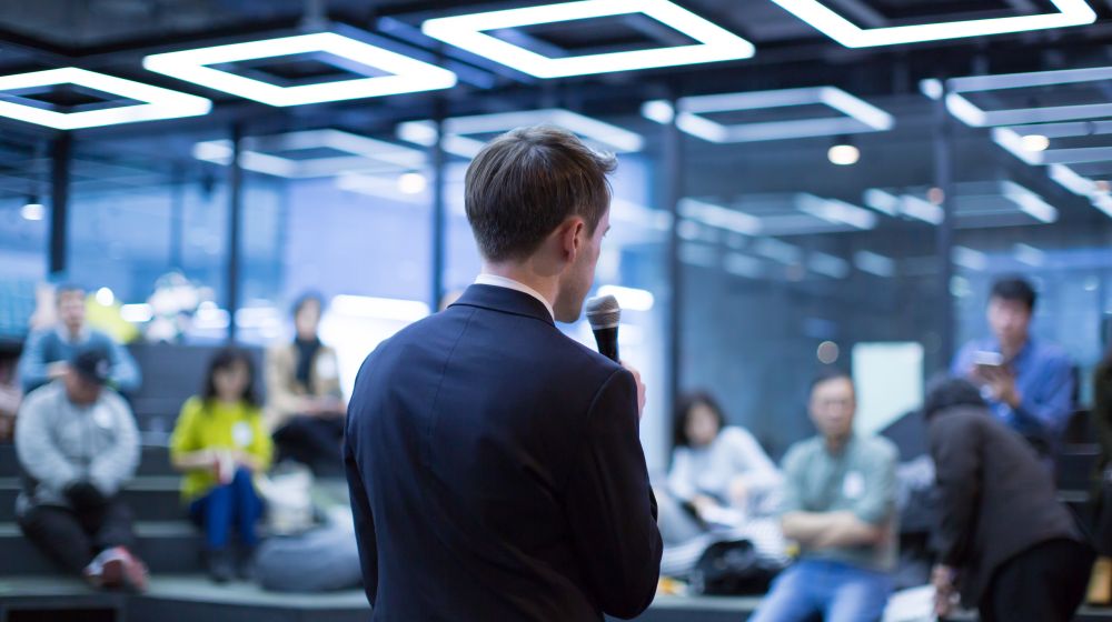 Entrepreneur standing in front of a room of investors pitching his idea