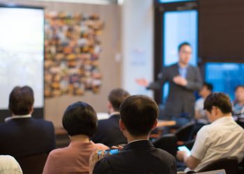 A group of angel investors sitting down watching an investment pitch presentation from a new entrepreneur