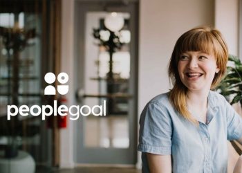 An image of a woman smiling in an office looking at the People Goal logo