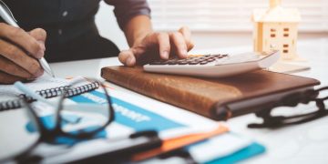 Business owner surrounded by tax paperwork and doing business tax calculations for the annual accounts