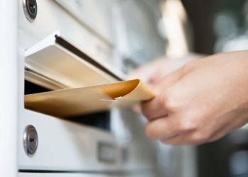 A person putting mail into a company mailbox which came as part of the virtual office services hired by the company