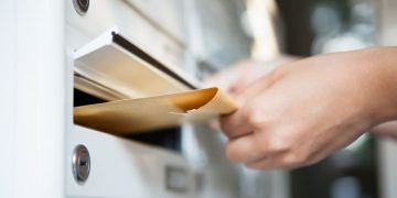 A person putting mail into a company mailbox which came as part of the virtual office services hired by the company