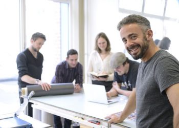 Business owner smiling in the foreground with employees in the background