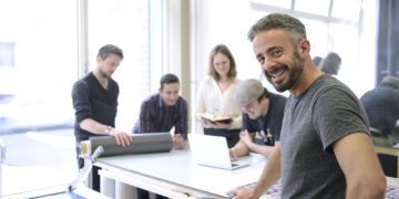 Business owner smiling in the foreground with employees in the background
