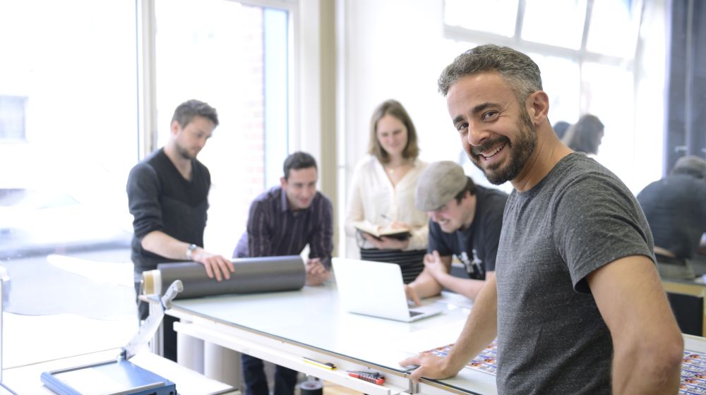 Business owner smiling in the foreground with employees in the background