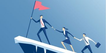 A leader reaching the flag at a top of a mountain and offering his hand to his team to bring them up the mountain too, showing great leadership qualities