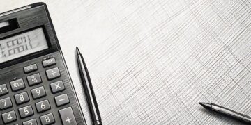 A calculator next to a pen on a desk in the office