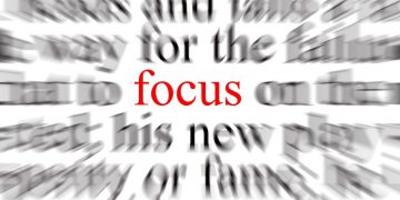 The word "focus" in red in the middle of blurred text, demonstrating how focus can bring clarity