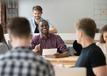 Group of colleagues smiling and laughing after one has said something funny in the office, symbolising a positive work culture and environment