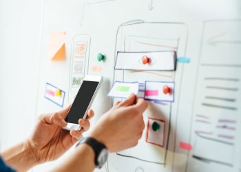 A designer choosing features on a pin board against a mobile design to increase user trust on an application