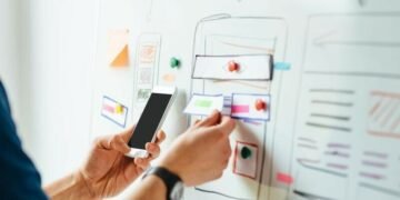 A designer choosing features on a pin board against a mobile design to increase user trust on an application