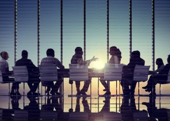 Team around conference table at office building discussing corporate venture deal