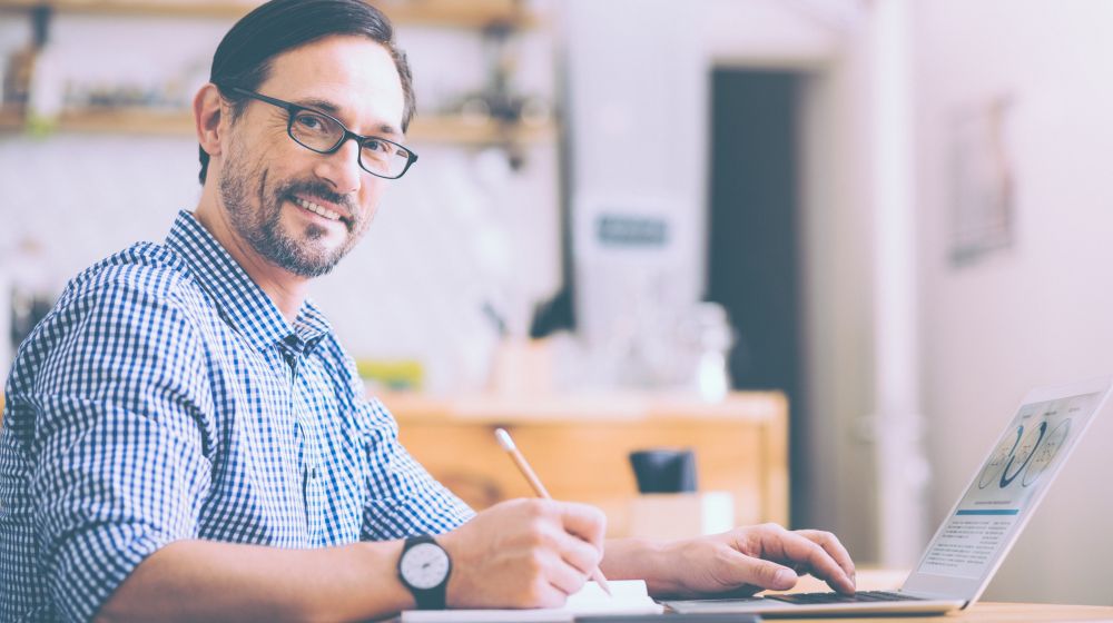 Entrepreneur sitting a desk smiling while he carries out the daily work of running a business