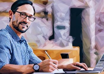 Entrepreneur sitting a desk smiling while he carries out the daily work of running a business