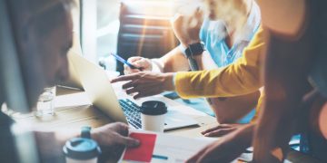 A group of entrepreneurs working around a table at a new business as an example of entrepreneurship in practice