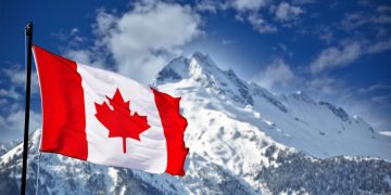 Canadian flag flying over a mountain, symbolising Canada