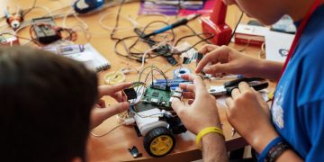 Two men constructing a robotic toy car using a raspberry Pi micro computer