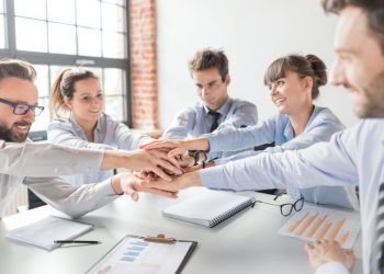 Team from a small business putting hands in the centre of the table to signify a great company culture