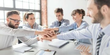 Team from a small business putting hands in the centre of the table to signify a great company culture