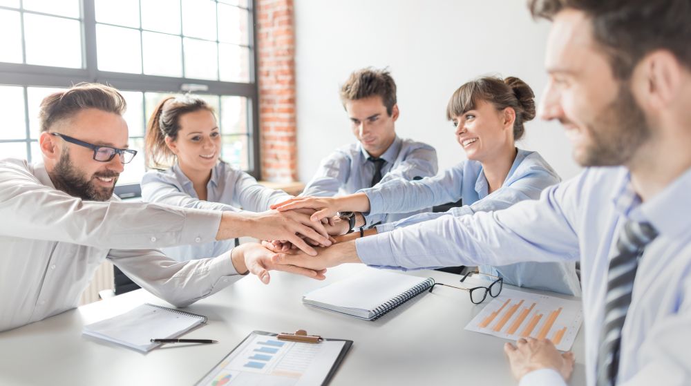 Team from a small business putting hands in the centre of the table to signify a great company culture