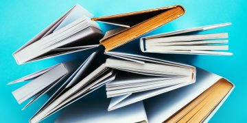 A series of business management books viewed from above on a blue background