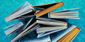 A series of business management books viewed from above on a blue background
