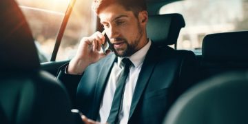 Businessman sitting in a car on the phone making a travel insurance claim on the go
