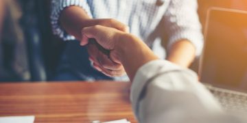A salesman shaking a customers hand and closing a sales deal in the process