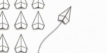 A series of white paper aeroplanes with one plane in red deviating symbolising how sometimes contray business advice is the best advice