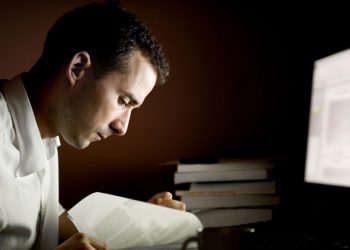 A man working late by a computer to show the idea of working 24/7