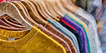 A series of t-shirts in different colours hanging on the clothes rack in a shop