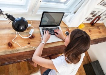 Female entrepreneur researching ways to grow her blog on a laptop, sitting by her desk