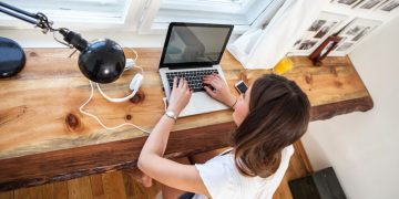 Female entrepreneur researching ways to grow her blog on a laptop, sitting by her desk