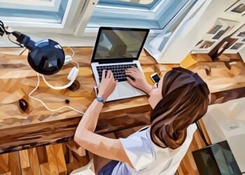 Female entrepreneur researching ways to grow her blog on a laptop, sitting by her desk