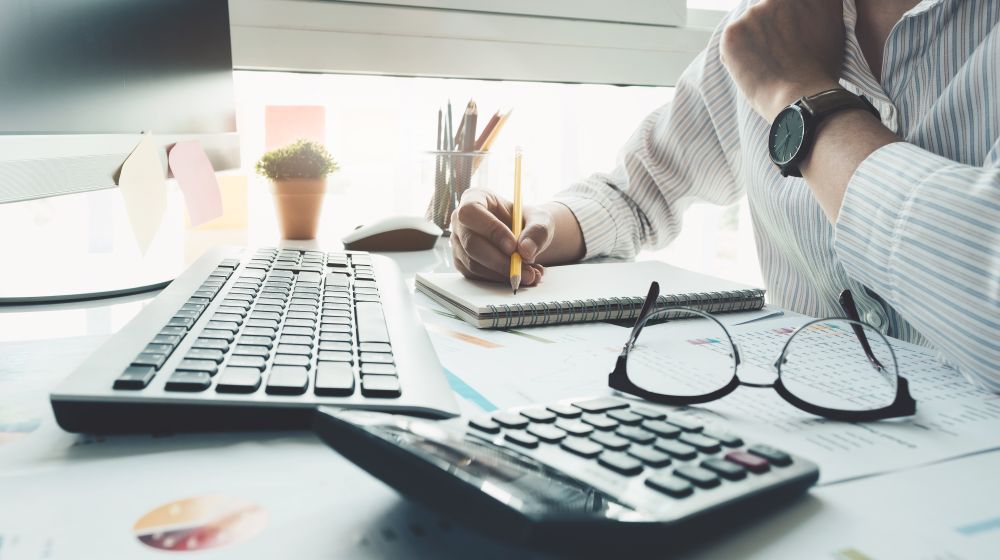 A entrepreneur using a computer, calculator and paper to work out how he can better budget