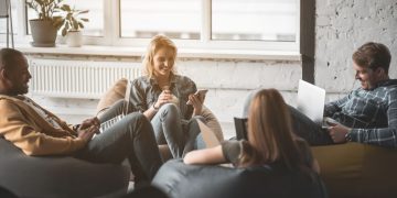 A team of colleauges sitting on bean bags working exampling how employees can be productive with more flexibility in the workplace