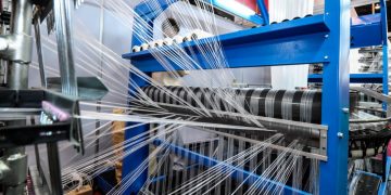 A working blue fabric loom spinning thread to be used for a clothing company