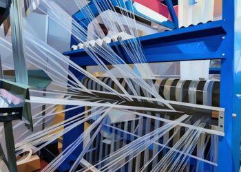 A working blue fabric loom spinning thread to be used for a clothing company