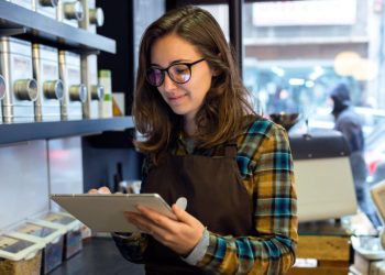A retail entrepreneur standing in her store using a tablet to control inventory levels as an example of a forward thinking retail business
