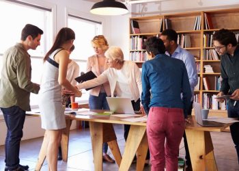 A group of employees around a table beitgn shown to use a collaboration tool