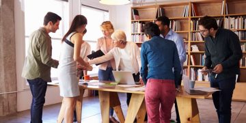 A group of employees around a table beitgn shown to use a collaboration tool