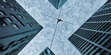 A man balancing to walk across a tightrope between corporate buildings, showing how important it is to plan for succession risks
