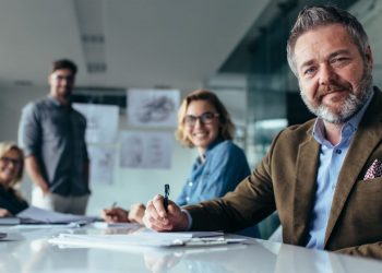 A group of non-execuitve directors sitting around a table in a board room, one in the foreground starting at the camera