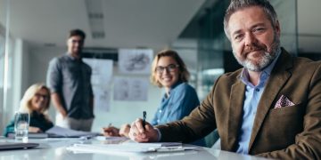 A group of non-execuitve directors sitting around a table in a board room, one in the foreground starting at the camera