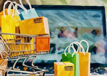A mini shopping trolley filled with packages in front of a laptop open on an eCommerce website, symbolsing how having the right eCommerce theme can make a difference to sales