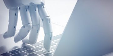 A robot hand using a laptop, symbolising how businesses can use intelligence